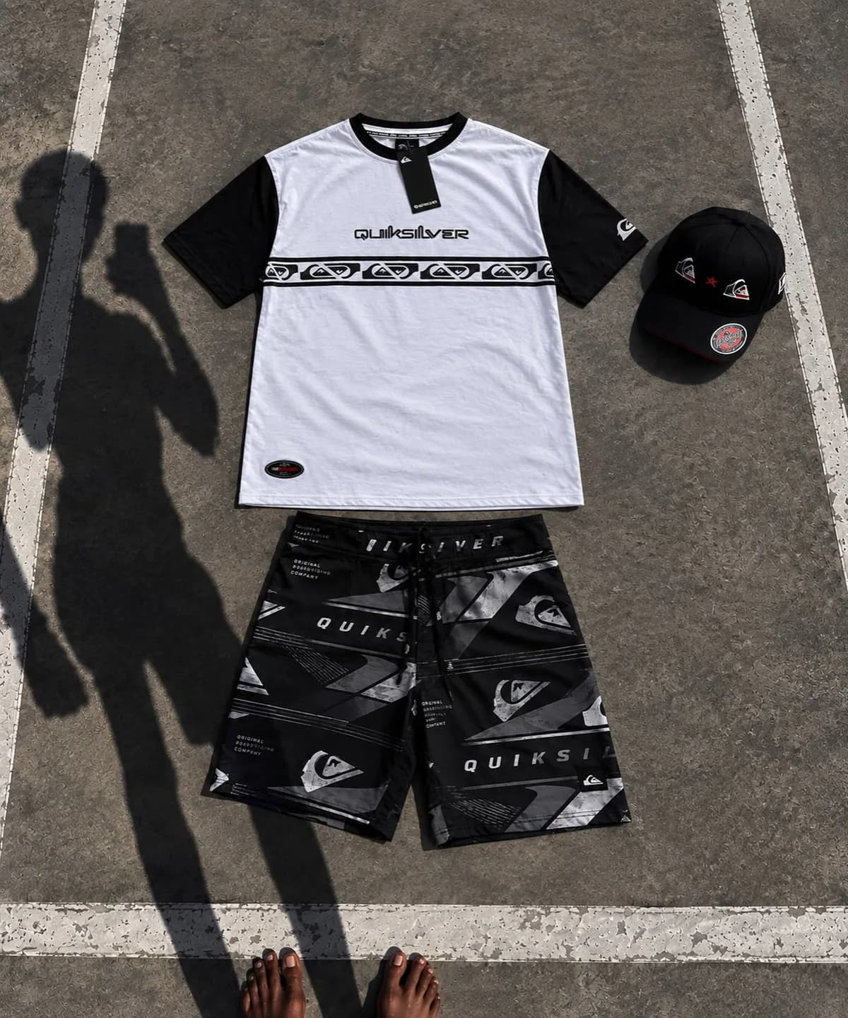 Kit Quiksilver branco e preto no estacionamento, com a sombra de quem fotografou no asfalto